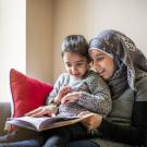 Woman holding a child and they are reading a book together