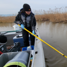 A person on a boat collecting water samples.